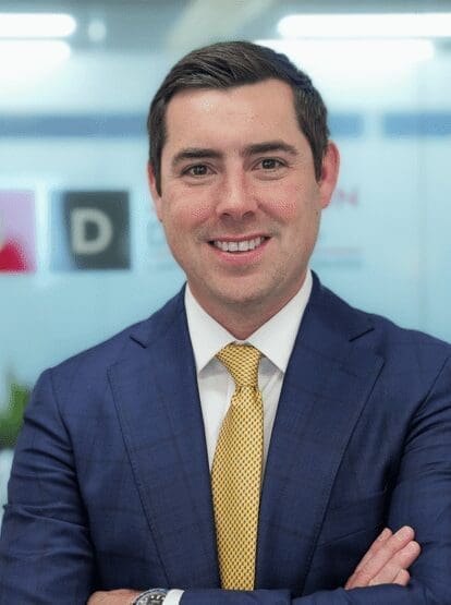 A man in a suit and tie smiling for the camera.