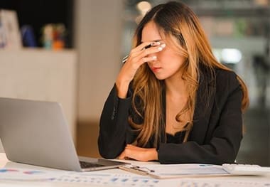 A woman sitting at a table with her hand on the face.