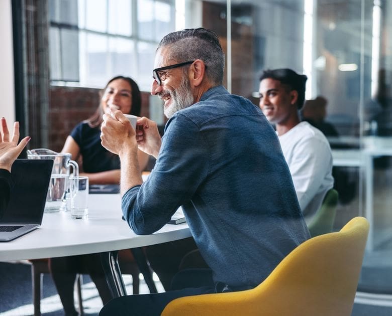 A group of people sitting at tables in front of a laptop.