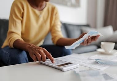 A person sitting at a table with papers and a calculator.