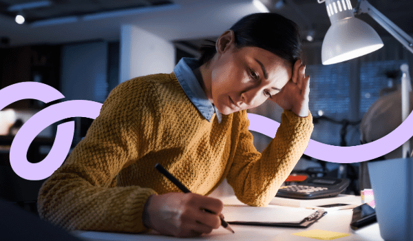 Woman writing at a desk, focused expression.