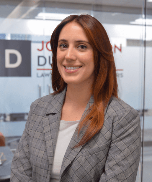 Smiling woman in office, wearing plaid blazer.