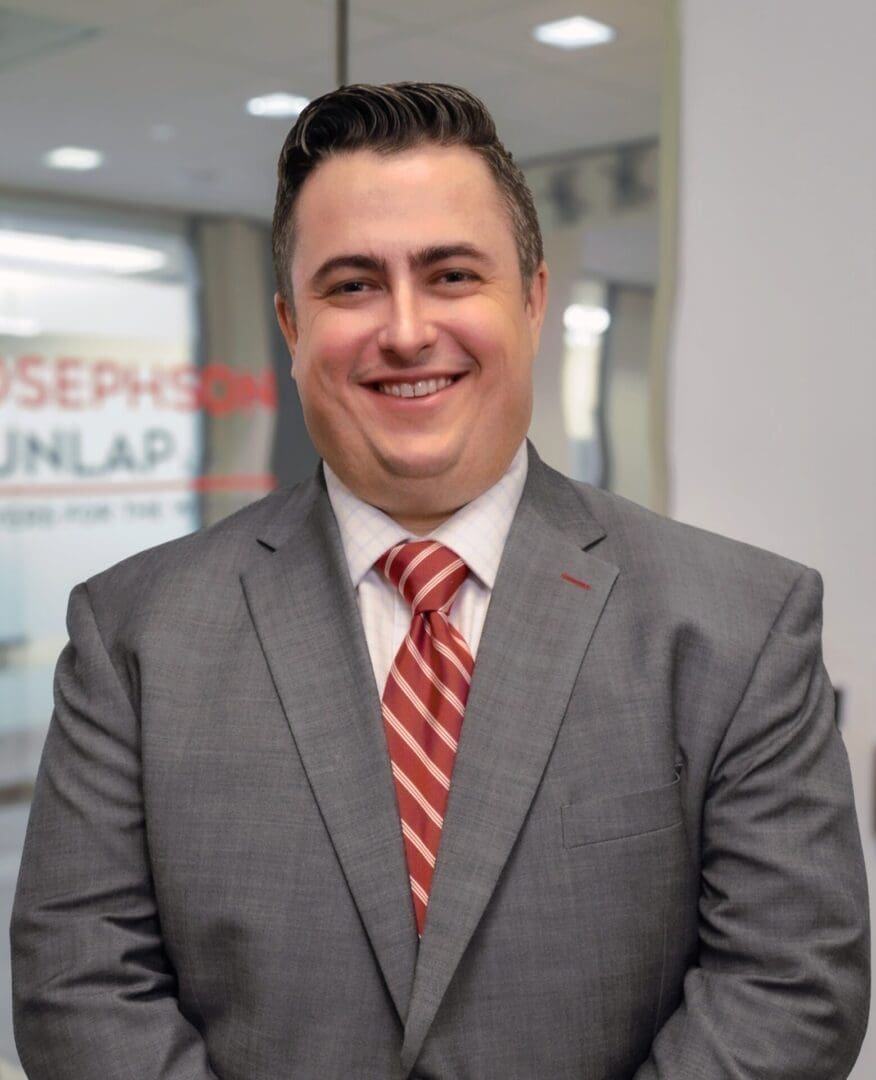 Smiling man in a gray suit indoors.