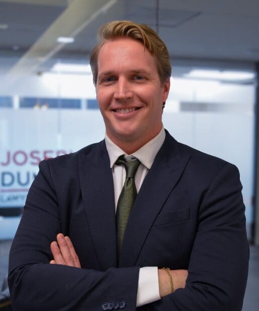 Man in suit smiling, arms crossed, indoors.